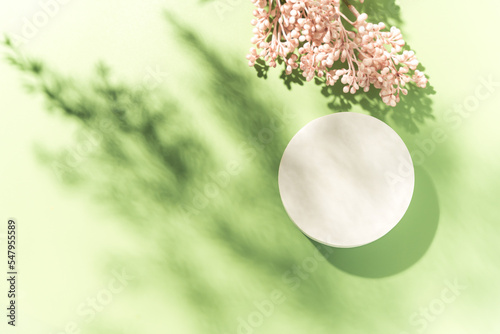 Фотография Empty white circle mockup podium for product presentation on a blooming spring flower background with hard light