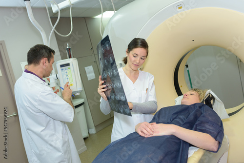 doctor showing xray results to patient layed on mri scanner