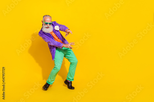 Full length photo of cheerful attractive man wear purple velvet jacket having fun discotheque empty space isolated yellow color background