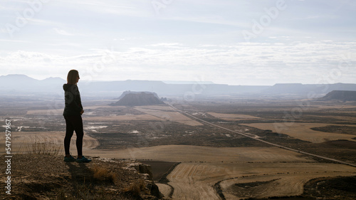 Silhouette of a woman in profile observing the arid desert plain from the top. Desert with gully mountains and sandstone plateaus. © ROM