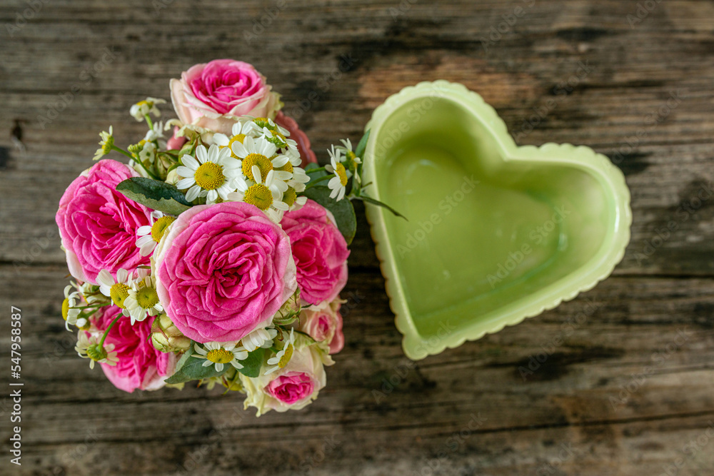 Heart bowls with roses on a wooden garden table Heart bowls with roses on a wooden garden table