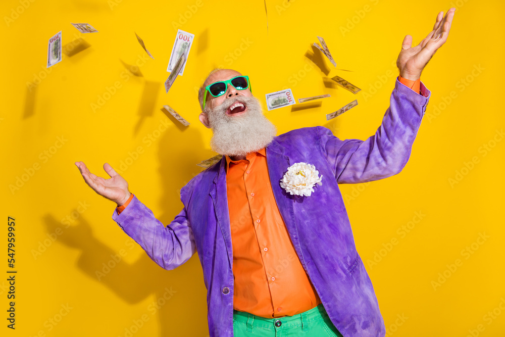 Photo of positive eccentric man granddad millionaire wear colorful bright costume rejoice usd banknotes isolated on yellow color background - obrazy, fototapety, plakaty 