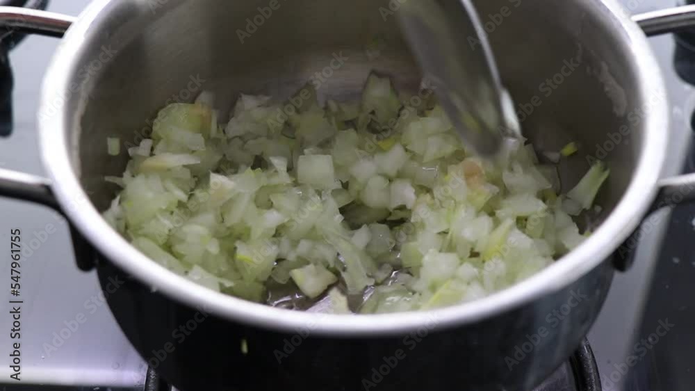 cut onions pouring into greasy metal pot on kitchen stove
