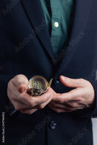 Male hands of a businessman in a business suit with a ring on his finger hold a pocket old time. Vertical orientation photo, business style.