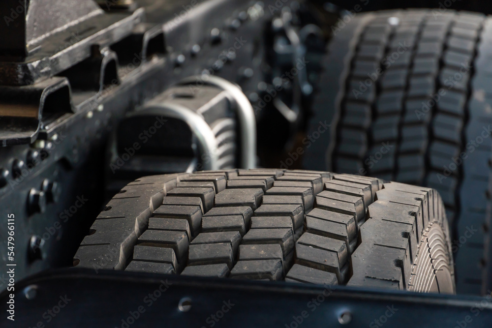 Exhibition of new large-sized equipment. Cars for cargo transportation. Big black truck tire close-up. Equipment for working in a quarry.