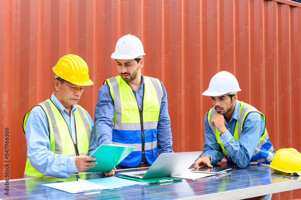 Group of container operators wearing helmets and safety vests meeting about logistics operations in container yards. Colleagues Talk About Logistics Operations Group of container operators wearing helmets and safety vests meeting about logistics operations in container yards. Colleagues Talk About Logistics Operations