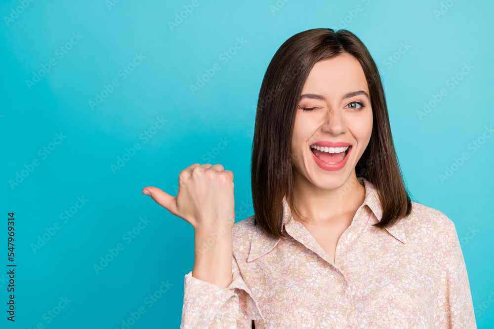Close up photo of positive lady wear stylish blouse wink eye thumb arm direct empty space cool discount isolated on cyan color background Close up photo of positive lady wear stylish blouse wink eye thumb arm direct empty space cool discount isolated on cyan color background
