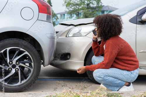 Asian women driver check for damage after a car accident before taking pictures and sending insurance. Online car accident insurance claim after submitting photos and evidence to an insurance company.