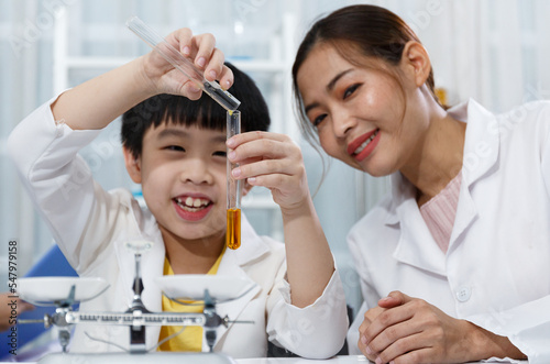 Asian boy and female teacher learn to experiment with mixing liquids in tubes. Closeup focus on science test tubes.