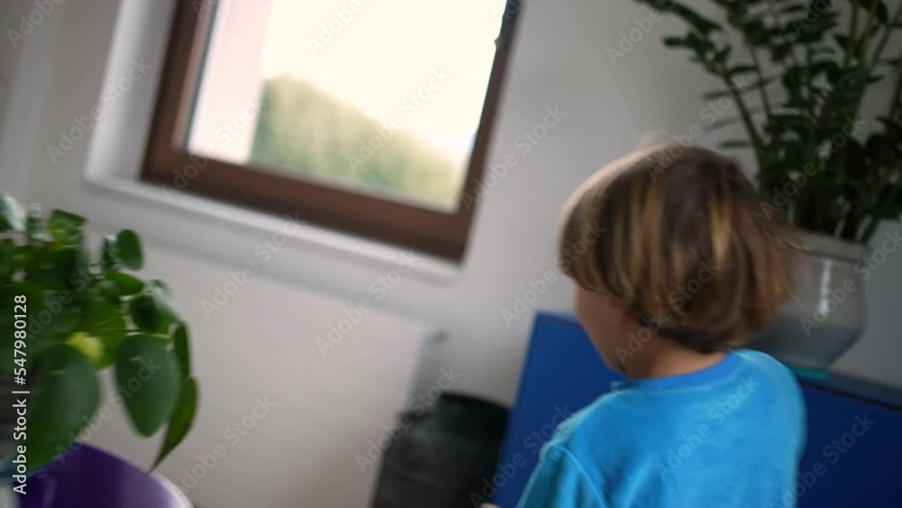 One happy child running at home interior. Back of small excited boy runs indoors in morning. Handheld slow motion footage