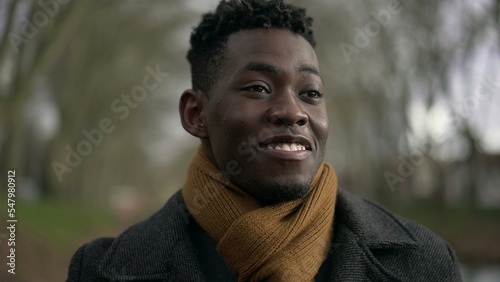 Happy young black man walking outside during winter feeling satsifaction and wellbeing