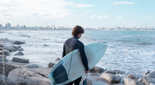 Surfer walking out to sea with a surfboard under his arm. Mar del Plata, Argentina.