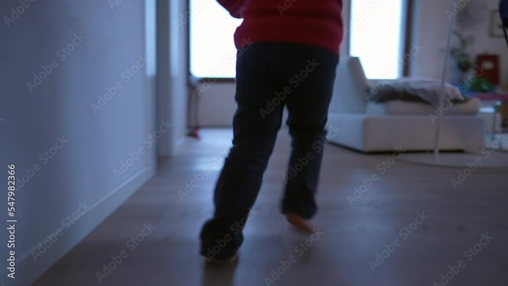 Happy child running indoors at home living room. Closeup kid feet runner inside modern house. Handheld footage
