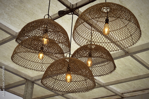 Yellow light bulbs that hanging in the roof with rattan woven ornament for vintage background and decorating inspiration