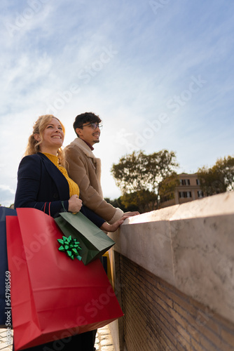 Young multiracial couple smiling holding shopping bags in the city