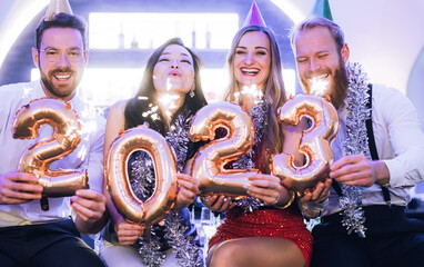 Men and women celebrating the new year 2023 with sparklers and wine