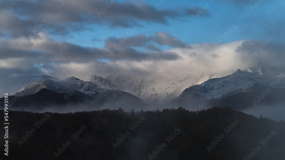 Snowy mountains landscape with clouds and fog