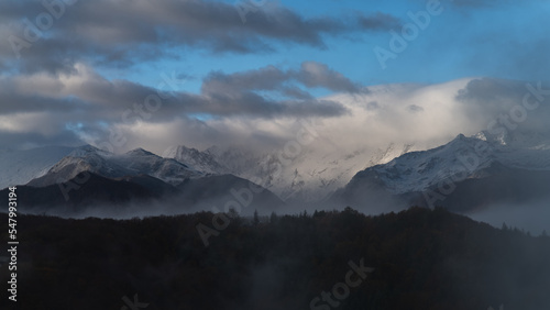 Snowy mountains landscape with clouds and fog