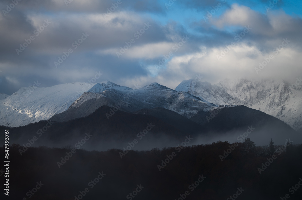 Snowy mountains landscape with clouds and fog