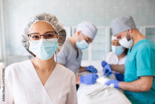Female surgeon with surgical mask at operating room. Young woman doctor in surgical uniform.