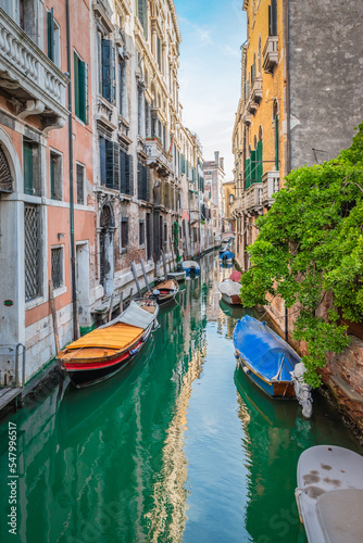 Moored boats on small canal in city of Venice, Italy.