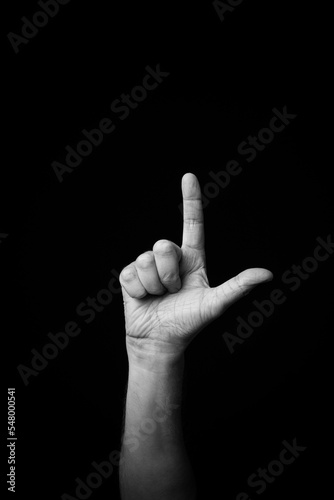 Hand demonstrating the French sign language letter 'L' with copy space