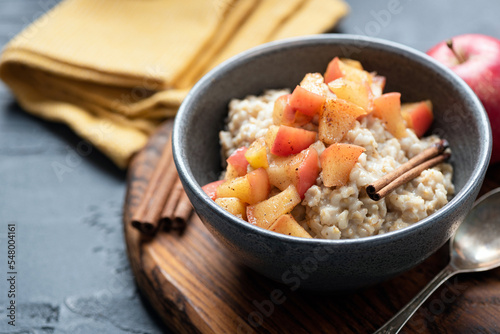Bowl of porridge oats with apple and cinnamon. Closeup view. Vegan, vegetarian breakfast, autumn comfort food