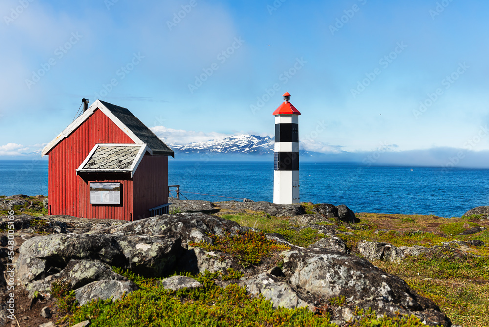 Remote Lynstuva lighthouse and a small red cabin in the Northern Norway coast, Lyngenfjord, at the northernmost point of Lyngen Peninsula with a panoramic views of the surrounding fjords and open sea 