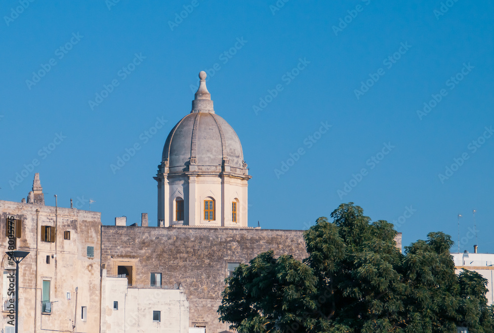 Cúpula de la Chiesa Rettoria Santa Teresa d'Avila desde la plaza Cristoforo Colombo en Monopoli, Italia. La cúpula semiesférica destaca sobre el resto de edificios en un día soleado de verano.