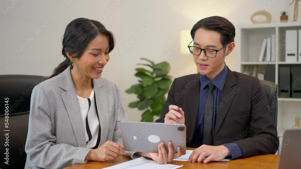 Smiling asian businesswoman showing tablet to her manager during a meeting in the office. secretary and boss in the office discuss new strategies and business development plans. Smiling asian businesswoman showing tablet to her manager during a meeting in the office. secretary and boss in the office discuss new strategies and business development plans.