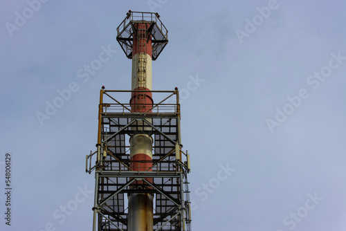 Bottom view of a tall factory chimney surrounded by a supporting frame
