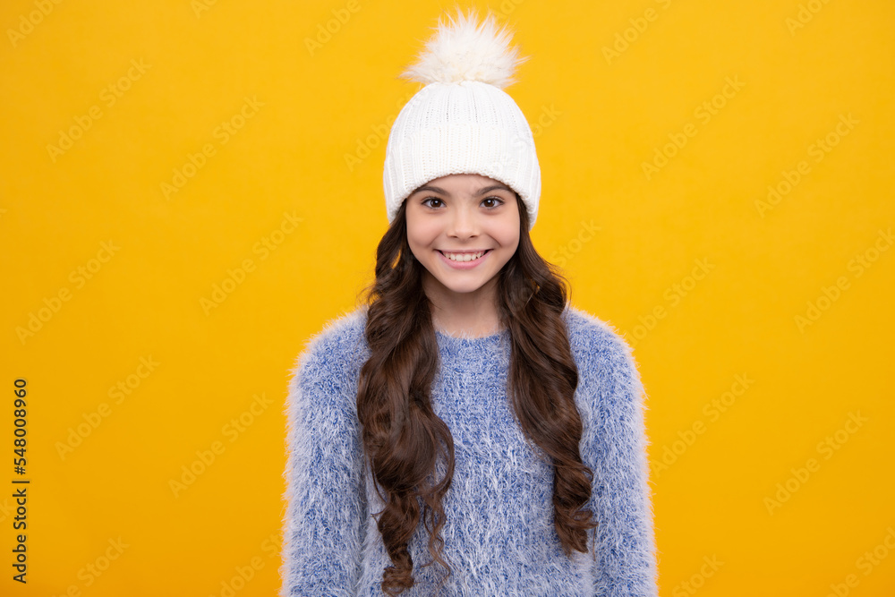 Teenager girl with winter hat over isolated yellow background. Winter christmas holidays, new year mood. Kids warm clothes. Happy girl face, positive and smiling emotions.