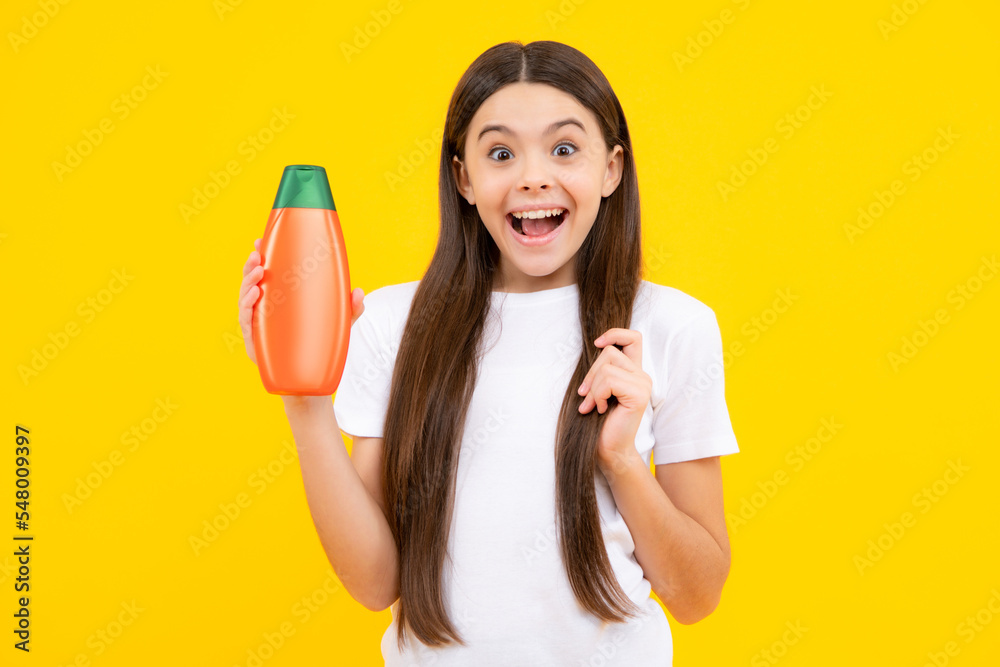 Happy teenager, portrait of child girl with bottle shampoo conditioners or shower gel. Kids hair care. Hair cosmetic product, shampoo bottle. Smiling girl. Happy teenager, portrait of child girl with bottle shampoo conditioners or shower gel. Kids hair care. Hair cosmetic product, shampoo bottle. Smiling girl.