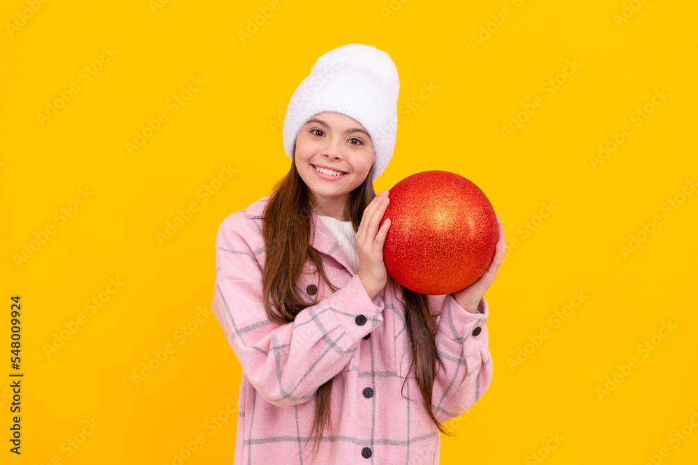 happy teen girl in winter hat hold christmas decorative ball on yellow background, christmas happy teen girl in winter hat hold christmas decorative ball on yellow background, christmas