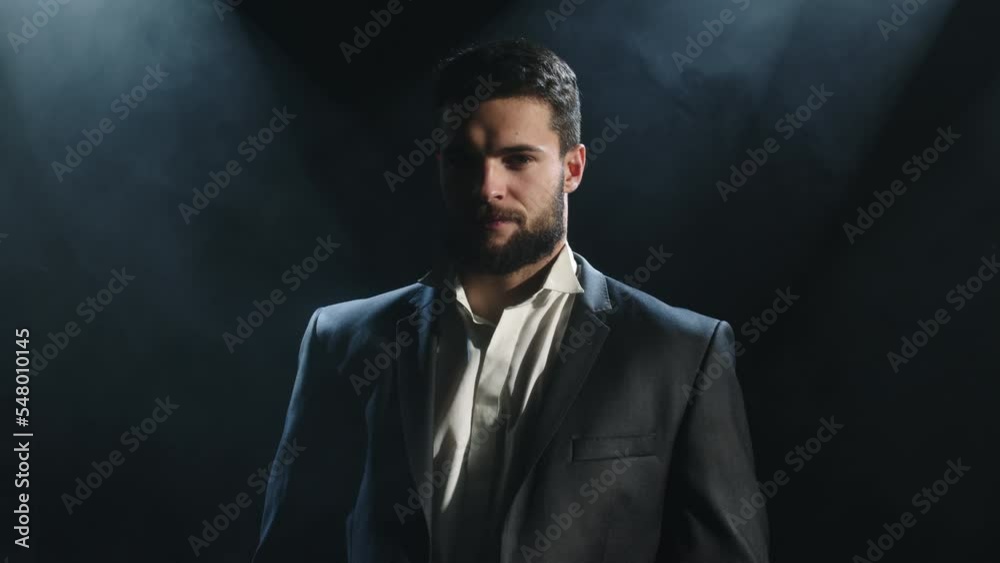 Portrait of a chic guy in a white shirt in a dark interior. A close-up of the man's sexy face is viewed with a camera in a smoke-filled room. A handsome gentleman poses in the home room at night
