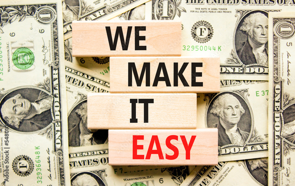 We make it easy symbol. Concept words We make it easy on wooden cubes. Beautiful background from dollar bills. Business motivational we make it easy concept. Copy space.