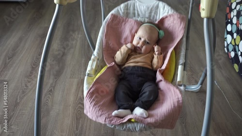Cute baby girl swinging in electric swings at home. Happy childhood and lifestyle concept
