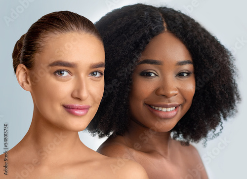 African american and caucasian young pretty women smiling on grey