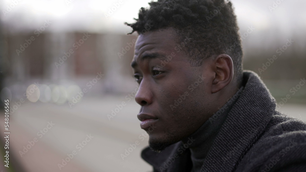 Pensive concerned black African man sitting on city sidewalk curb feeling emotional pain Pensive concerned black African man sitting on city sidewalk curb feeling emotional pain