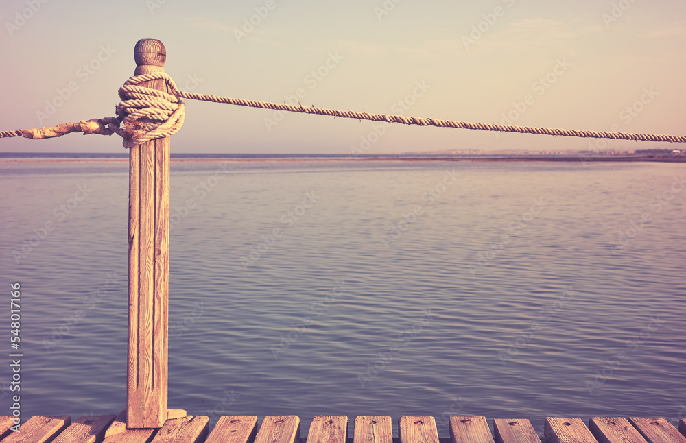 Obraz premium Wooden pier rope railing, selective focus, color toning applied.