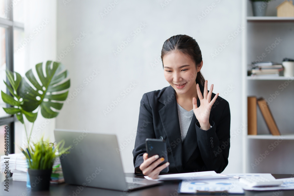 Cute young Asian business woman talking and video conferencing on mobile phone with customer at work. Cute young Asian business woman talking and video conferencing on mobile phone with customer at work.