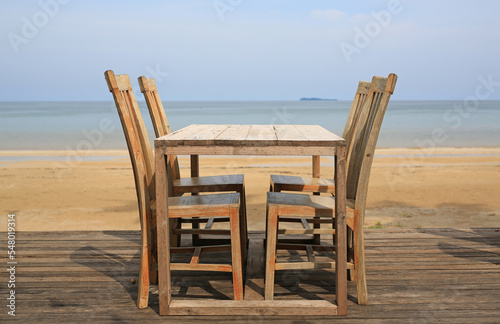Empty wood table and chairs near the beach.