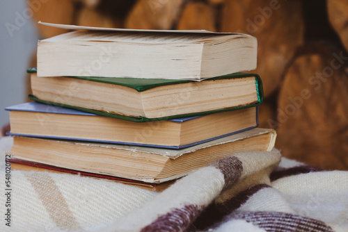 A stack of old books on the woolen blanket on wooden background in vintage style. Literature, education, hobby, reading and lifestyle