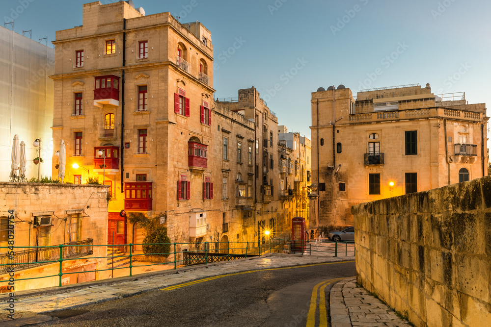 Valletta, Malta - The traditional maltese houses with balconies and walls of Valletta illuminated before sunrise