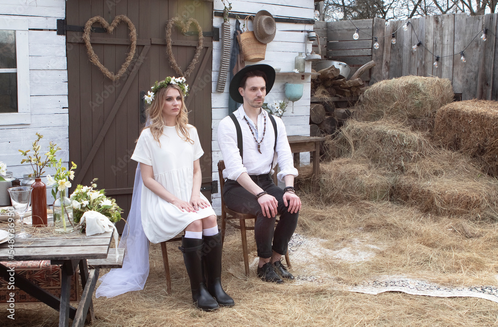 country bride in a white short dress and groom in a white shirt in the village wedding, boho style. country bride in a white short dress and groom in a white shirt in the village wedding, boho style.