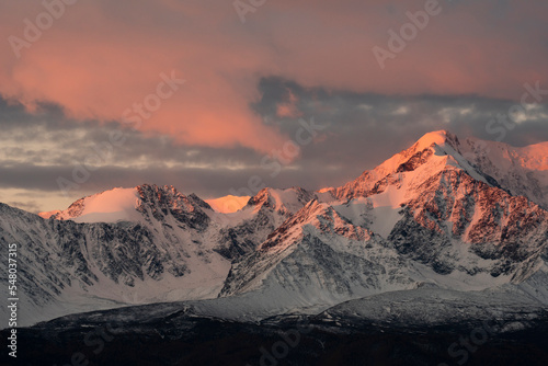 Russia. The South of Western Siberia, the Altai Mountains. Illuminated by the crimson morning light, the peaks of the North Chui Mountain Range along the Chui tract.