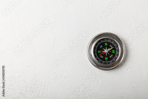 Classic round compass on a white texture background. Symbol of tourism with a compass, travel with a compass and outdoor activities. Close-up. Place for text. copy space
