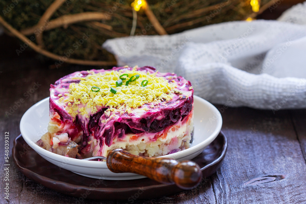 Dressed herring, raditional Soviet festive salad of herring and vegetables in a New Year's decoration.