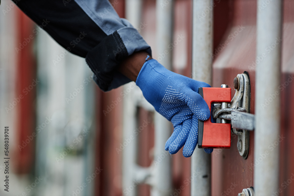 Close up of worker opening lock on container door in shipping docks, copy space - obrazy, fototapety, plakaty 