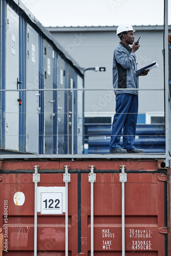 Graphic portrait of male worker standing on containers in shipping docks